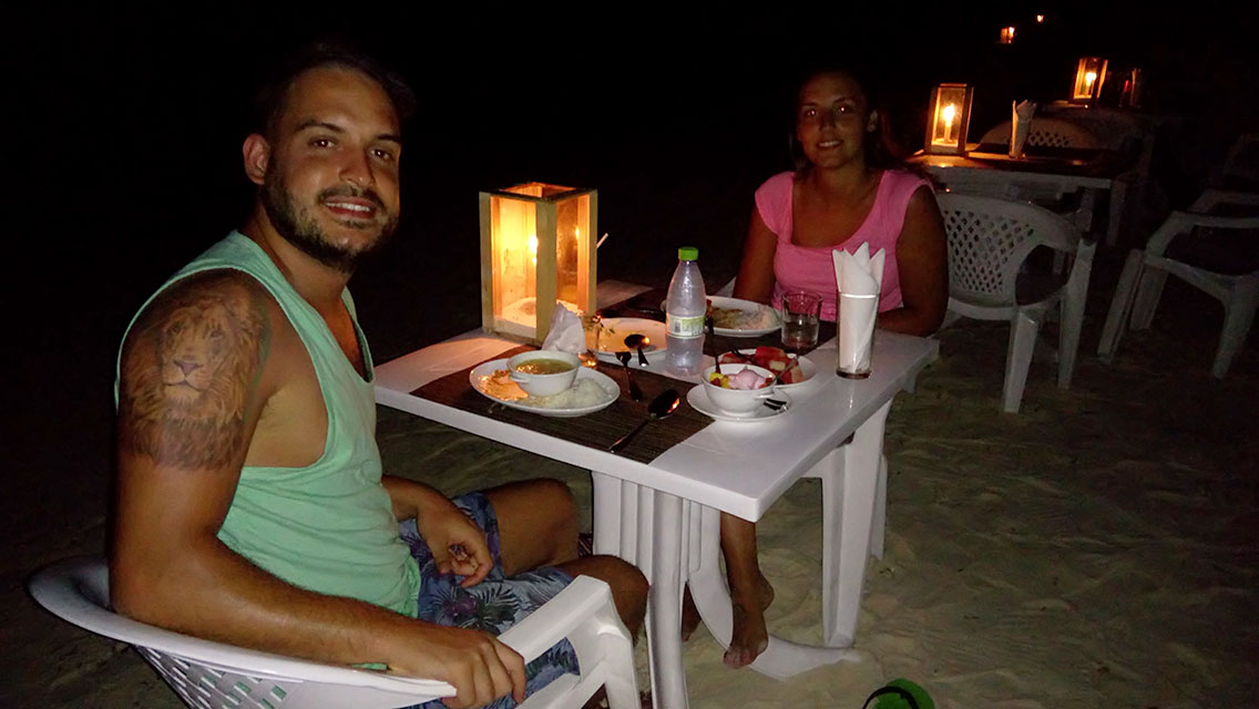 Pareja cenando por la noche en la arena de la playa de Maafushi