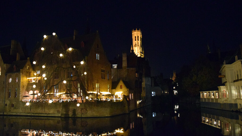Edificios históricos de Brujas iluminados durante la noche.