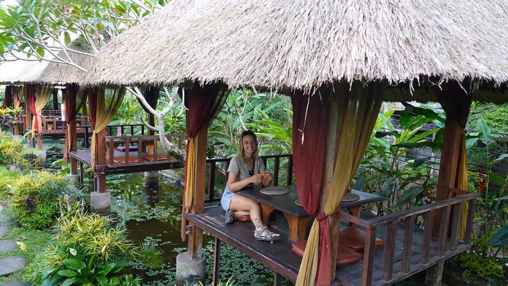 Noelia comiendo en el restaurante Waroeng de Koi tradicional balinesa con vistas al agua.