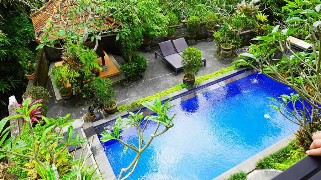 Piscina exterior rodeada de vegetación en el KT. Kuaya Home Stay en Ubud.