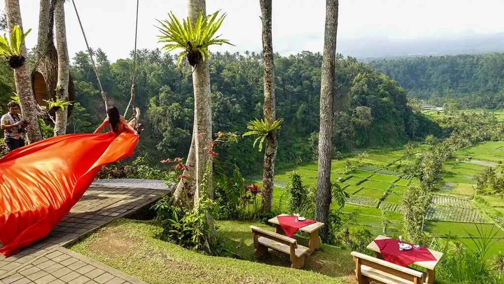 Mujer posando en un columpio gigante de los arrozales con un vestido largo de vuelo.