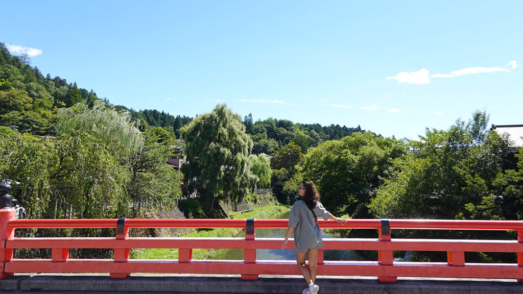 Puente rojo Nakabashi encima del río en Takayama con un bosque en el fondo