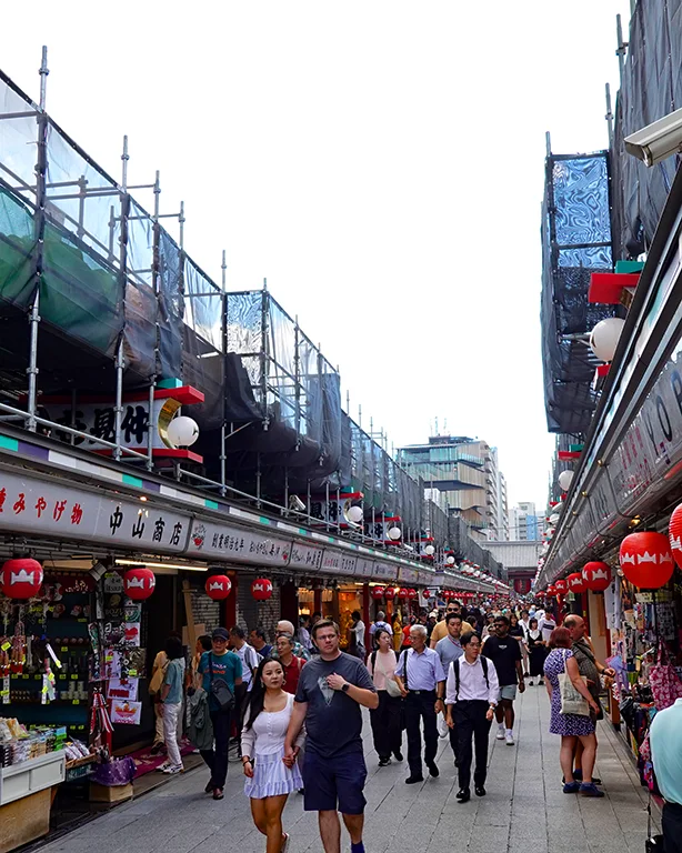 La calle comercial Nakamise-dori llena de gente y tiendas de souvenirs abiertas.