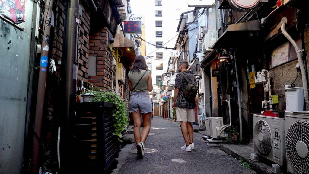 Joan y Noelia caminando por una calle estrecha de Tokio, explorando la ciudad a pie como parte de nuestra guía de transporte.