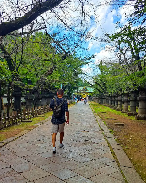 Joan caminando por un pasillo de farolillos de piedra en el parque de Ueno