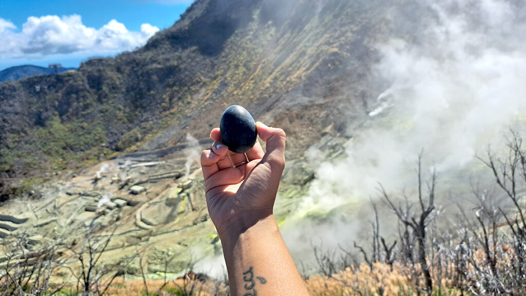 Noelia sosteniendo un huevo negro en Owakudani con humos de fondo.