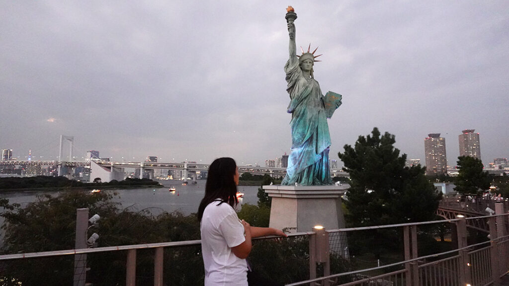 Noelia en la pasarela lateral de madera junto a la Estatua de la Libertad de Odaiba.