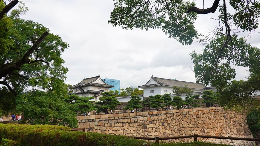 Vista frontal del Castillo de Osaka rodeado de árboles.