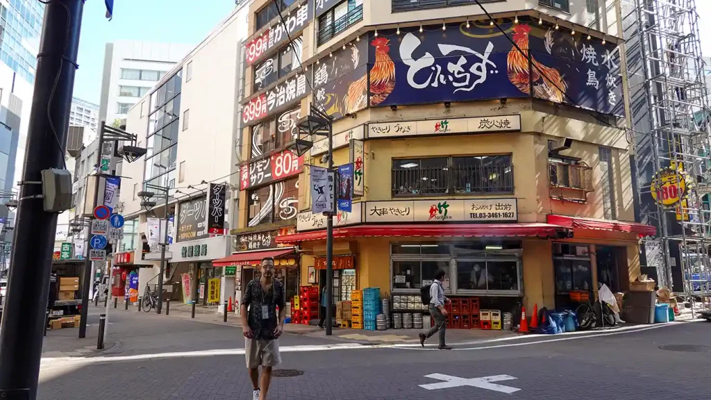 Un cruce de calles animado en Shibuya, Tokio, con edificios llenos de carteles y letreros japoneses coloridos.