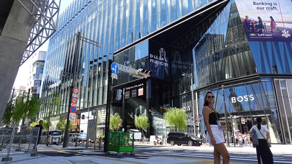 Noelia posando en la moderna entrada de cristal y diseño del centro comercial Ginza Novo.