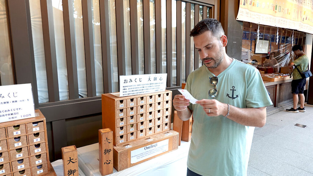 Joan leyendo un papel de la fortuna omikuji en el patio interior del Santuario Meiji en Tokio.
