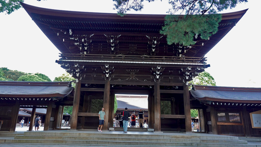 Cruzando la gran puerta Minami Shinmon de madera tallada en el Santuario Meiji.