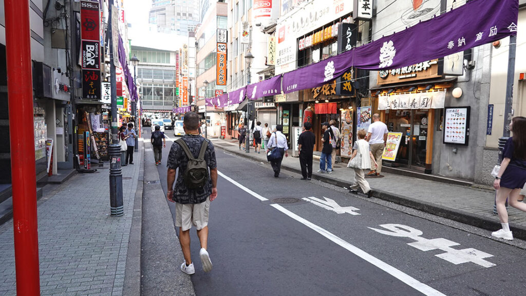 Joan paseando y mirando escaparates en una colorida calle peatonal de tiendas de moda en Harajuku.