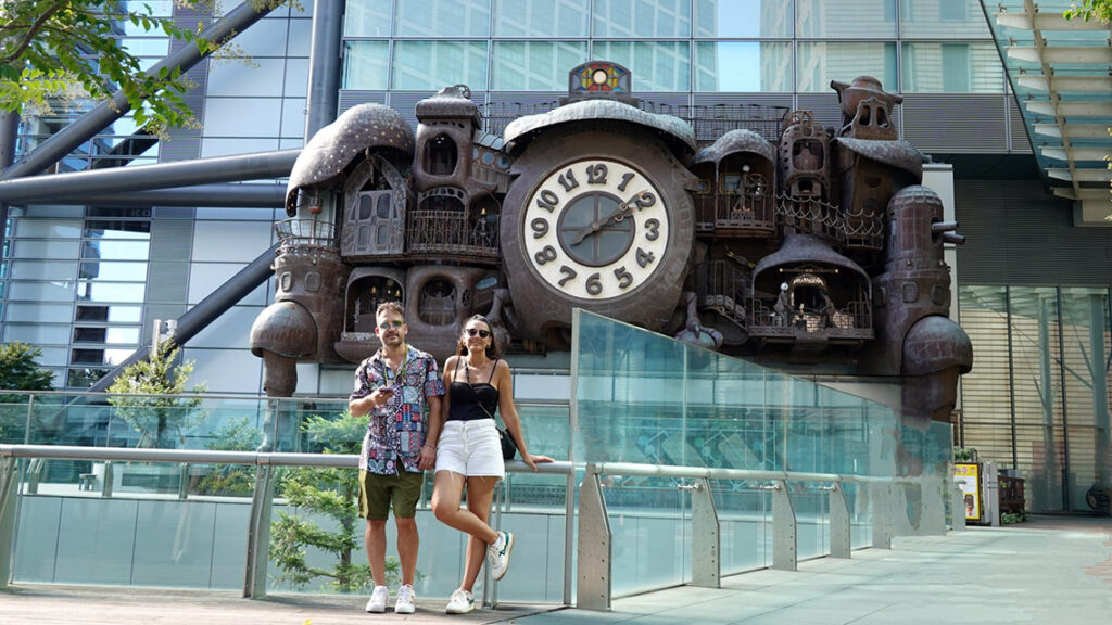 Noelia y Joan posando sonrientes frente al gigantesco Reloj de Ghibli diseñado por Hayao Miyazaki en Shiodome.