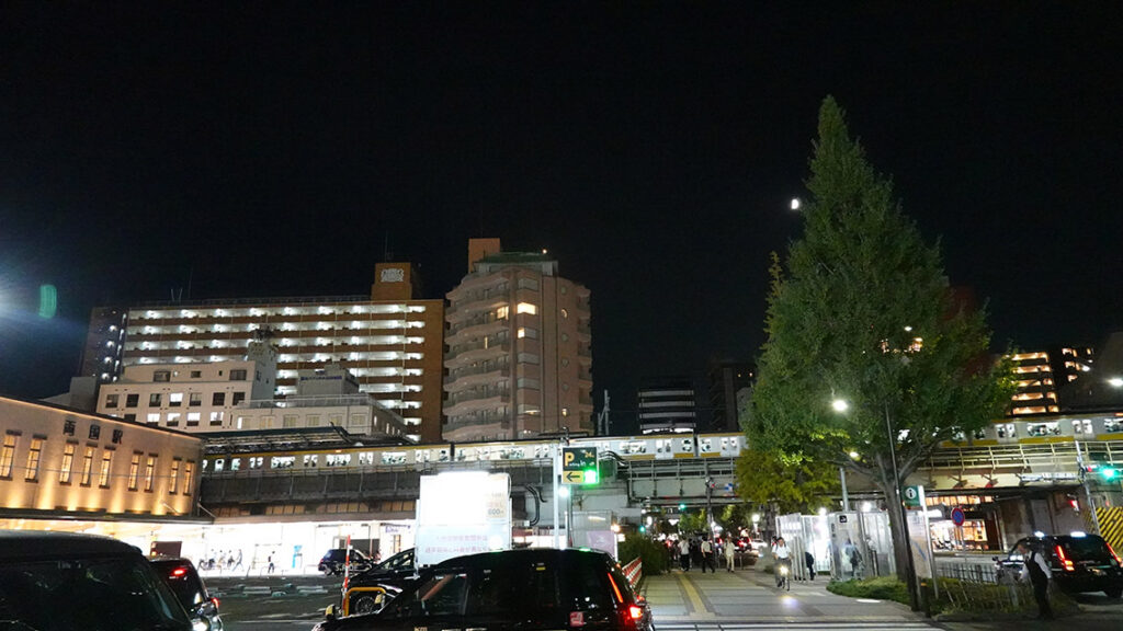 Fachada exterior con tejado verde de la estación de tren JR Ryogoku de noche.