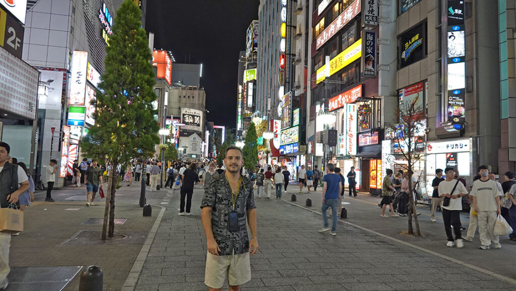 Joan rodeado de carteles de neón iluminados de noche en Shinjuku.