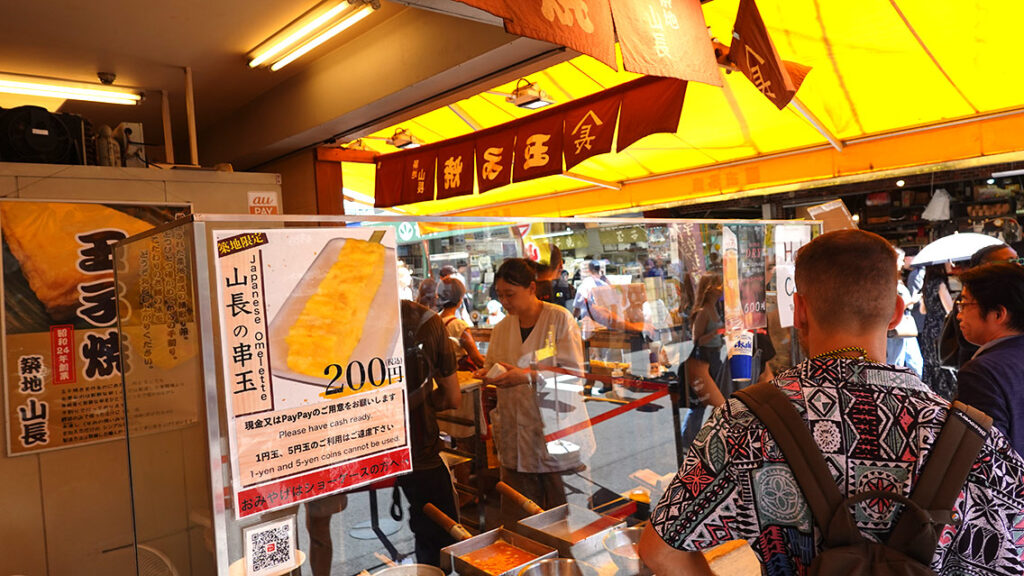 Joan comprando un pincho de tortilla japonesa tamagoyaki en el famoso puesto de Tsukiji Yamacho en Tokio.