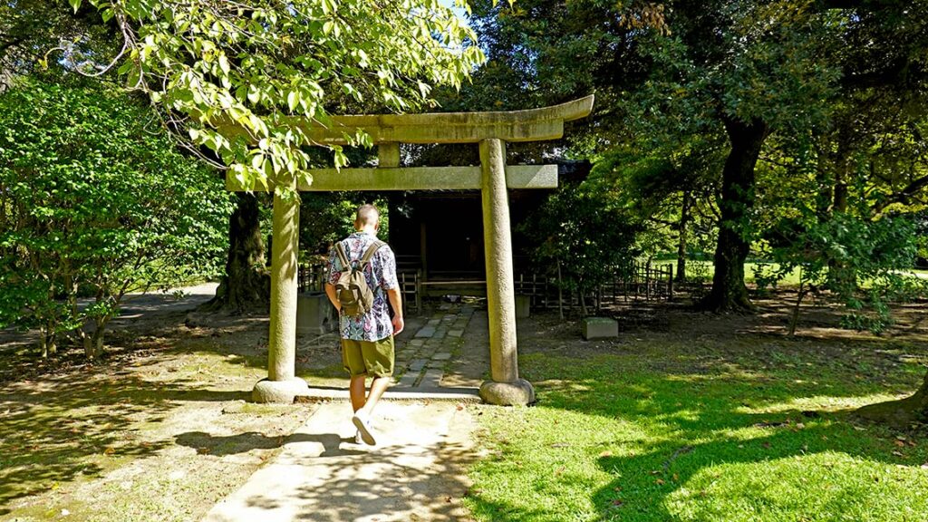 Joan debajo del torii de madera del antiguo santuario Inari dentro de los Jardines de Hamarikyu en Tokio.