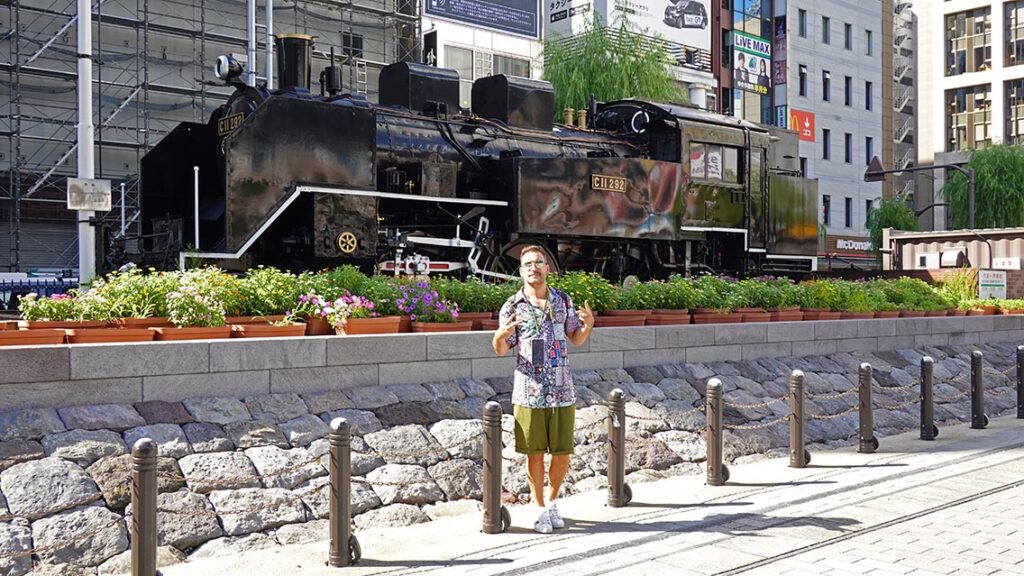Joan frente a la antigua locomotora de vapor restaurada en la SL Square de la estación de Shimbashi en Tokio.