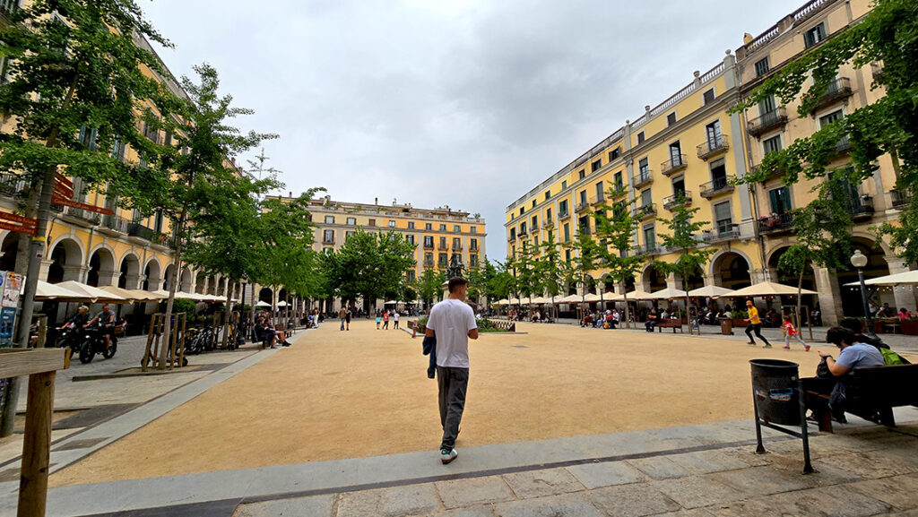 Joan paseando por una plaza llena de apartamentos