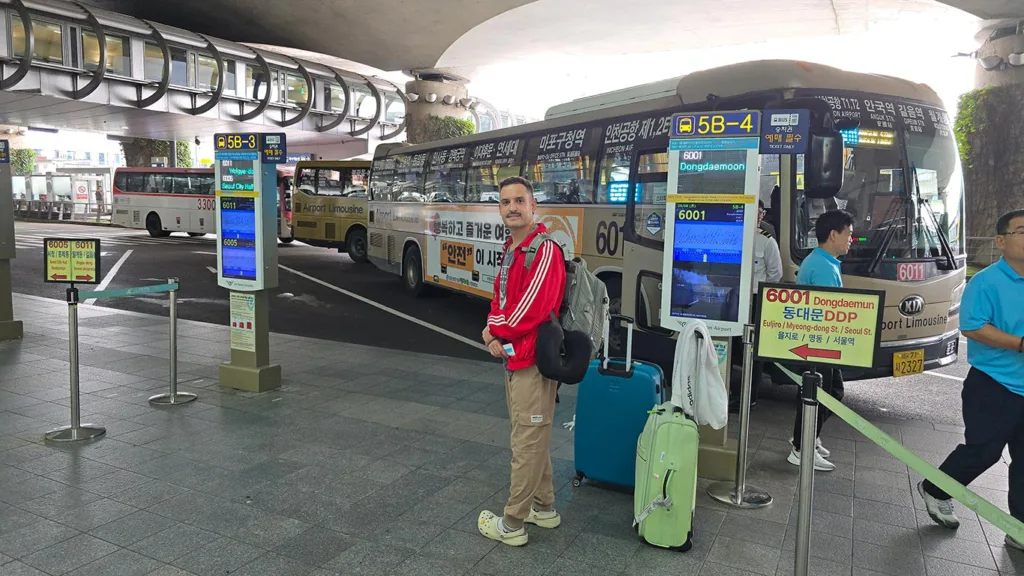 Joan esperando con las maletas en la parada del autobús Airport Limousine fuera del aeropuerto