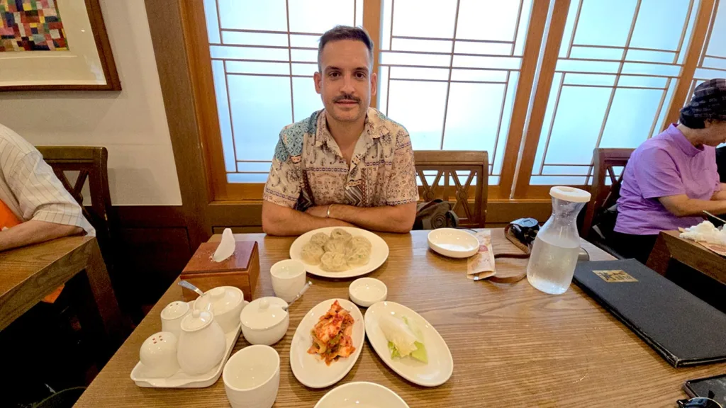 Joan sentado en una mesa rodeado de dumplings y platos de guarnición