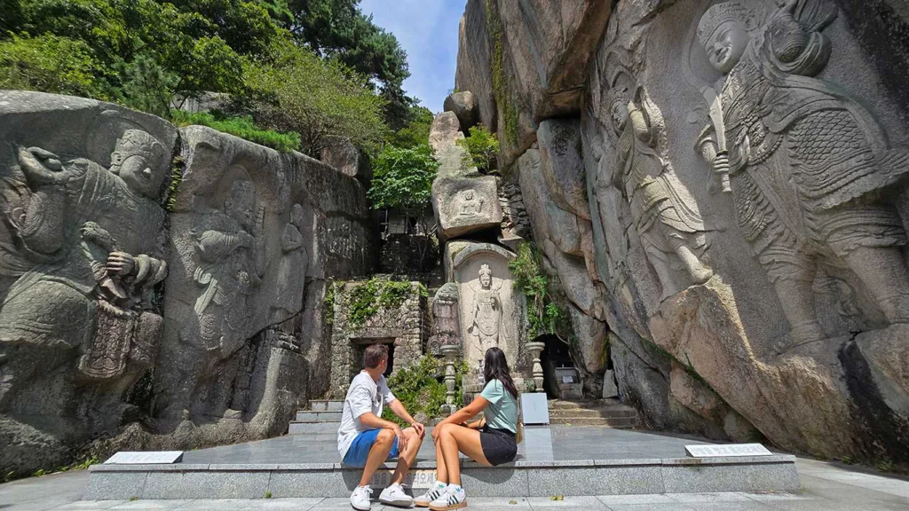 Nosotros sentados en el Templo Seokbulsa en Busan, contemplando las esculturas grabadas en las paredes de roca