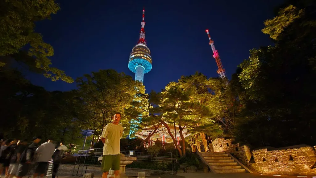 Joan en la base de la N Seoul Tower iluminada de muchos colores durante la noche