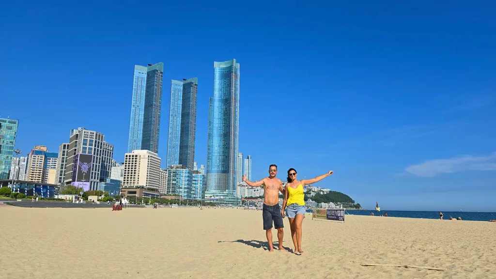 Joan y Noelia en la arena de la playa Haeundae rodeados de rascacielos