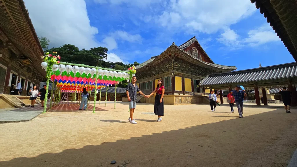 Interior de uno de los patios en el recinto del templo, gente paseando y farolillos de colores