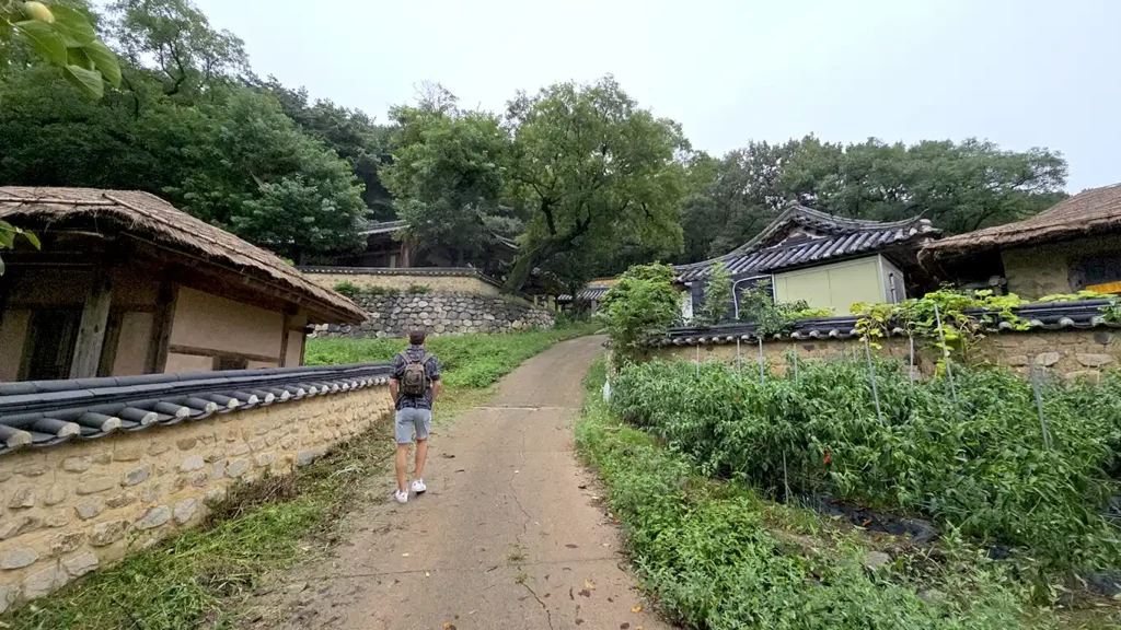 Joan paseando entre casas de techo de tejas y casas de techo de paja