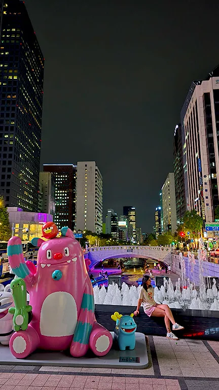 Noelia en el arroyo de Cheonggyecheon con figuras coreanas