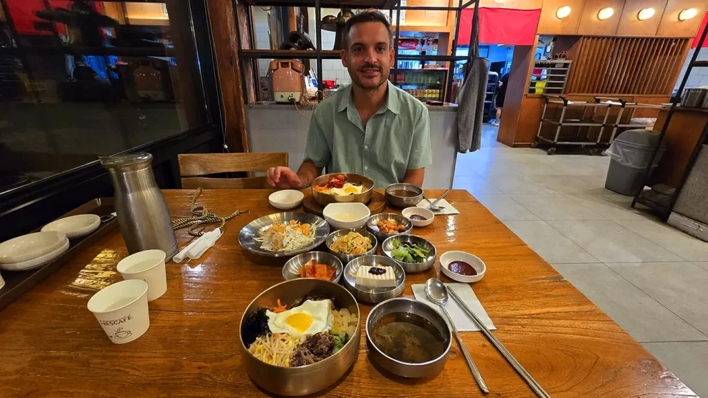 Joan sentado en el restaurante rodeado de platos para comer