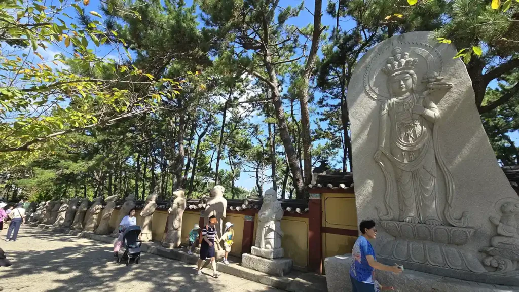 Las 12 estatuas del zodiaco y gente paseando en la entrada del Templo Haedong Yonggungsa
