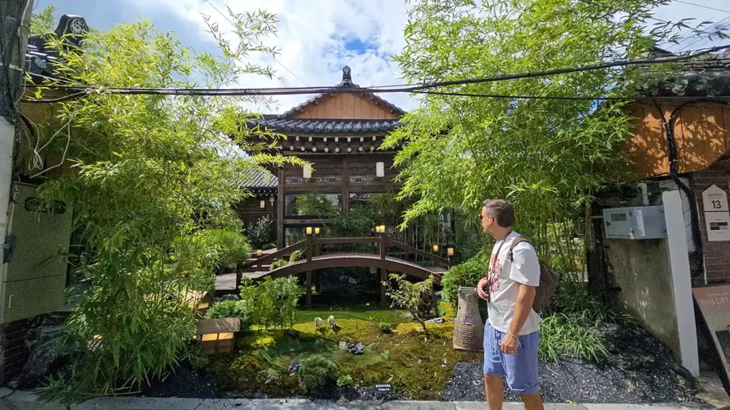 Una casa hanok reconvertida en una cafetería, con un puente encima de un pequeño lago
