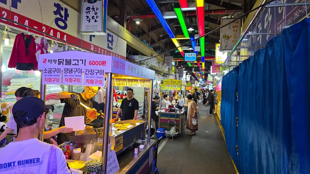 Pasillo del interior del mercado con puestos callejeros y gente comprando comida tradicional