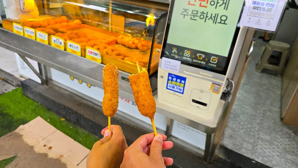 Sosteniendo dos Korean Hot Dog, muy virales entre los jóvenes coreanos en Seúl