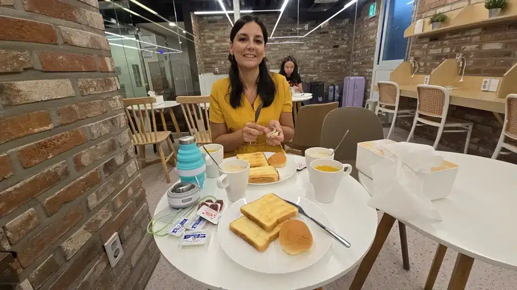 Noelia desayunando tostadas con mermelada en el desayuno gratis en el hostal Oyo Hostel Myeongdong 6 de Seúl, en la zona de Myeong-dong