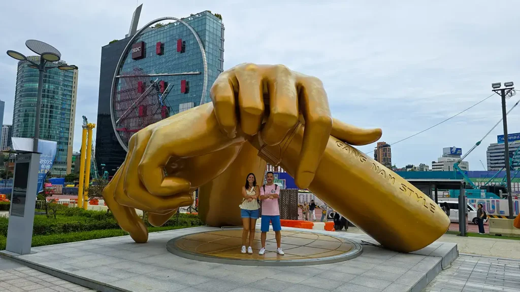 Dos Viajeros Viajando bailando en la Estatua de Gangnam Style del cantante PSY