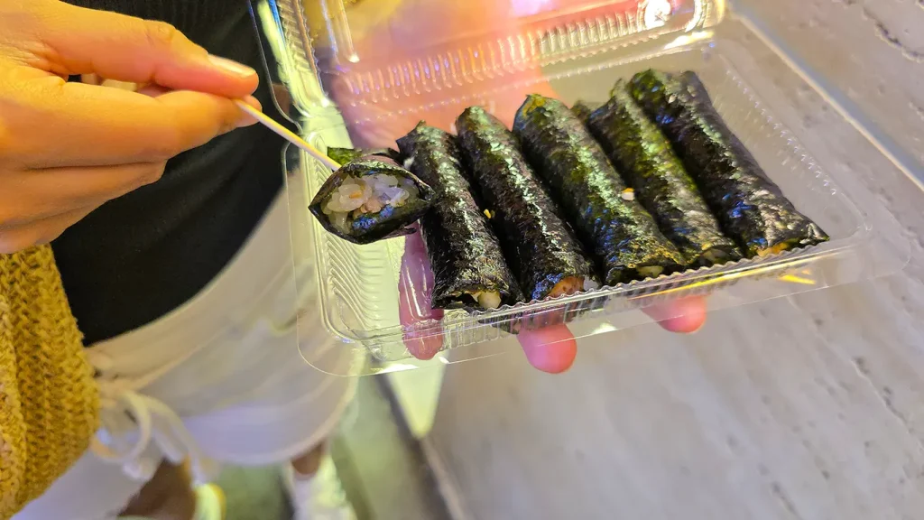 Noelia sosteniendo un pack de Kimbap comprados en el mercado Myeongdong