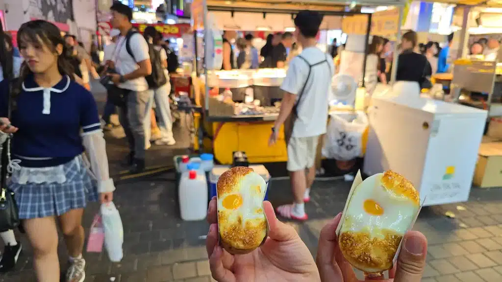 Dos viajeros Viajando comiendo Gyeran-ppan en el mercado nocturno de Myeongdong en Seúl