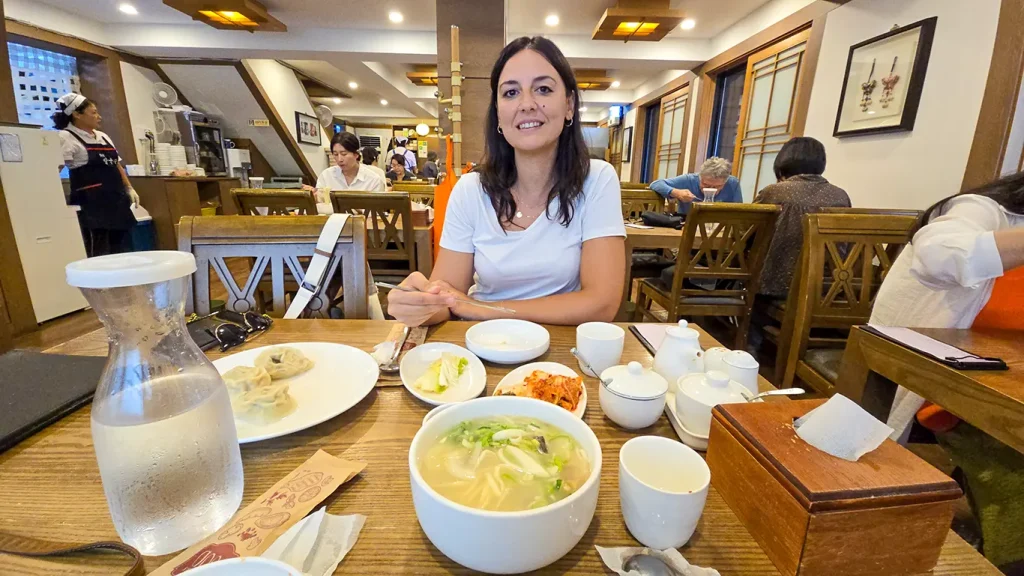 Noelia junto a un plato kalguksu en el comedor del restaurante Hwangsaengga Kalguksu