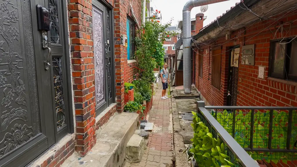 Joan en una calle residencial de casas de ladrillo rojo con techos tradicionales