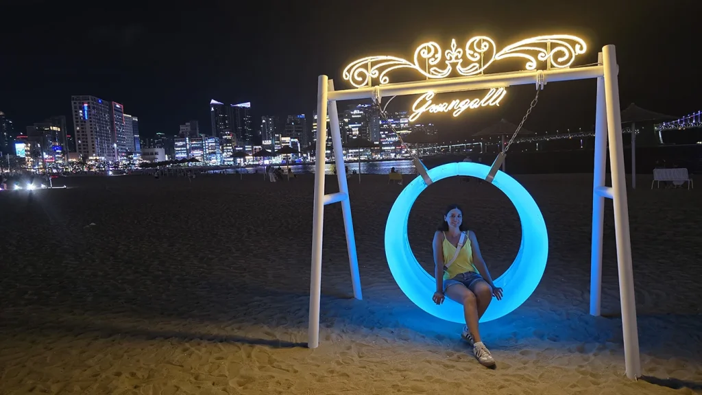 Noelia en un columpio iluminado en la playa Gwangalli de Busan