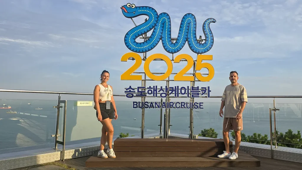 Nosotros en cartel de una serpiente azul, y el texto amarillo llamado 2025 Busan Air Cruise 