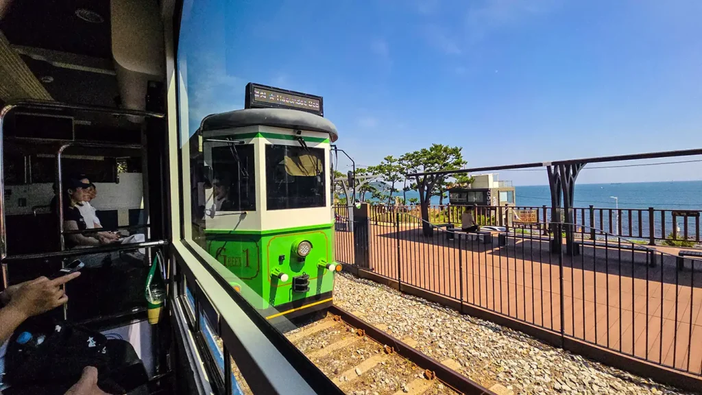Tren color verde en Haeundae Blue Line Park, la estación y el mar de fondo