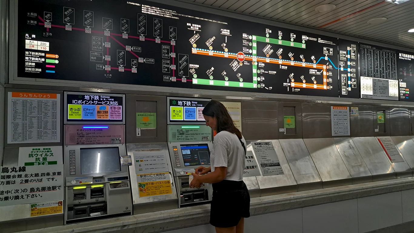 Noelia averiguando cómo pagar el transporte en japón en una máquina de billetes en una estación de Japón