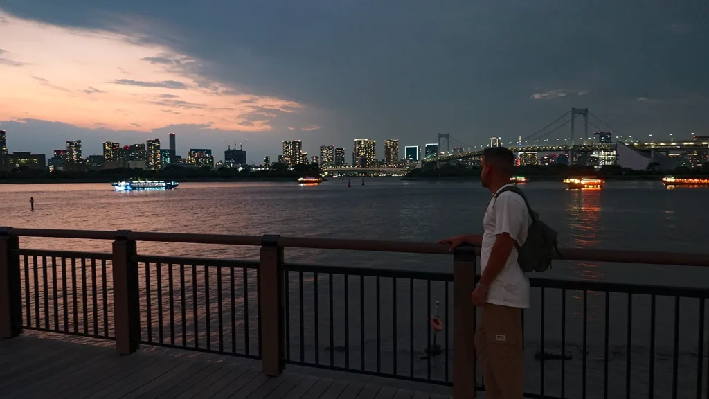 Joan en un sendero de Odaiba Park mirando el atardecer sobre el Rainbow Bridge.