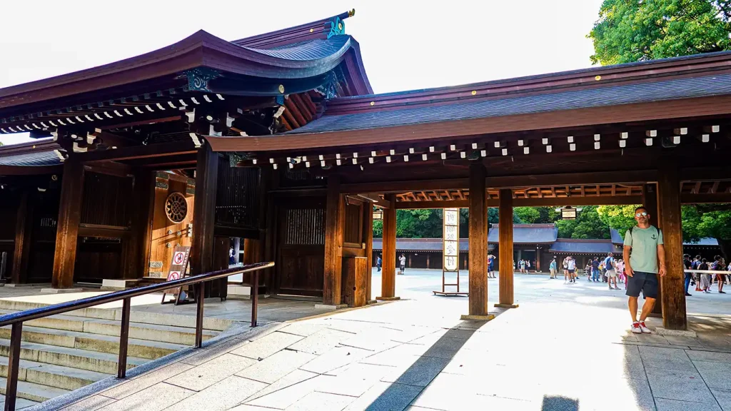 Posando bajo una de las grandes puertas de madera tradicionales en el Santuario Meiji, uno de los mejores lugares que ver en Harajuku, Tokio.