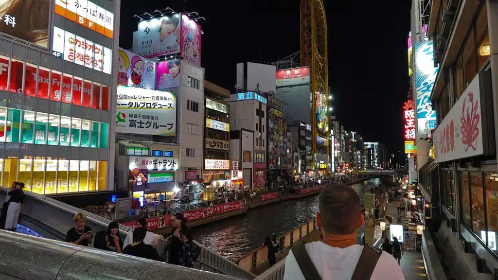 Joan de espaldas mirando el canal de Dōtonbori y el letrero del Glico Man con gente paseando en Osaka.